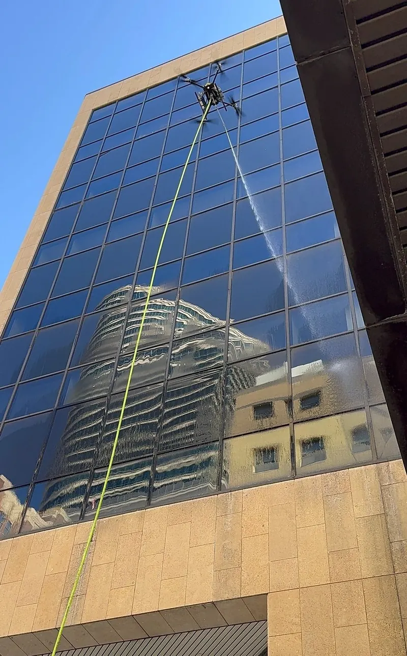 Drone spraying the glass curtain wall of a tower
