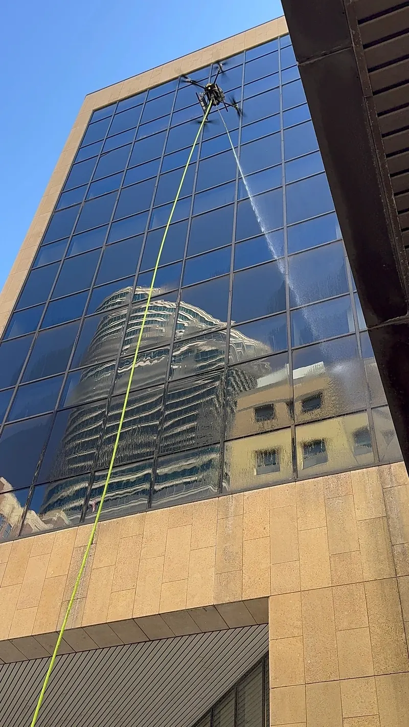 Drone spraying the glass of a tower