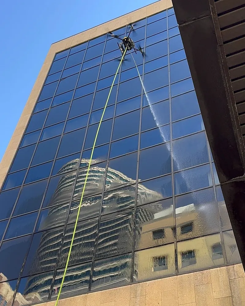 FlyWash drone spraying the glass curtain wall of a tower